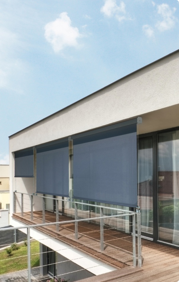 Tende da esterno installate su un balcone moderno, con struttura in alluminio e tessuto blu scuro, che forniscono ombra e privacy.